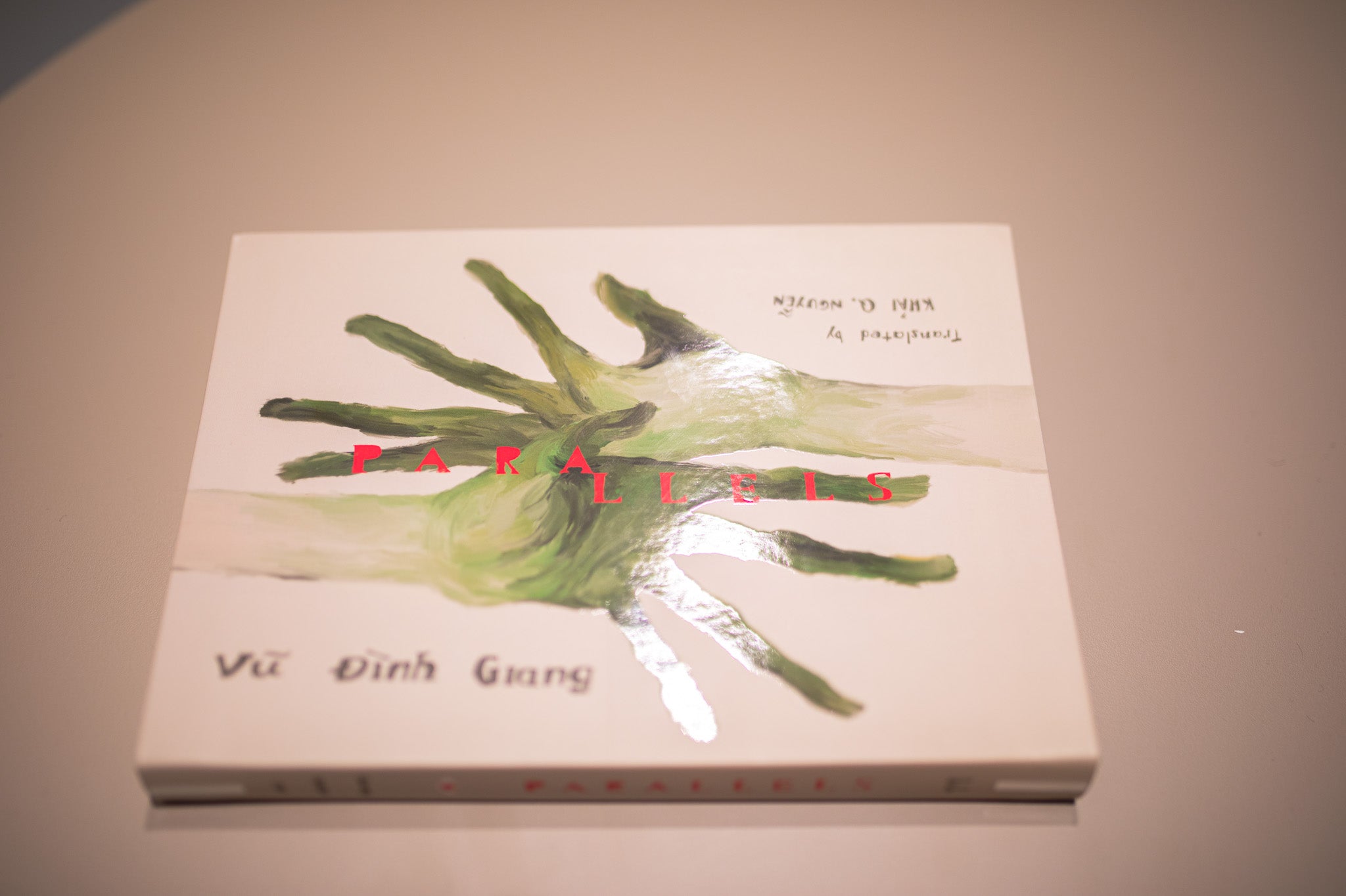 Book cover with green hand design and  a beige background, detail on UV spot finishing